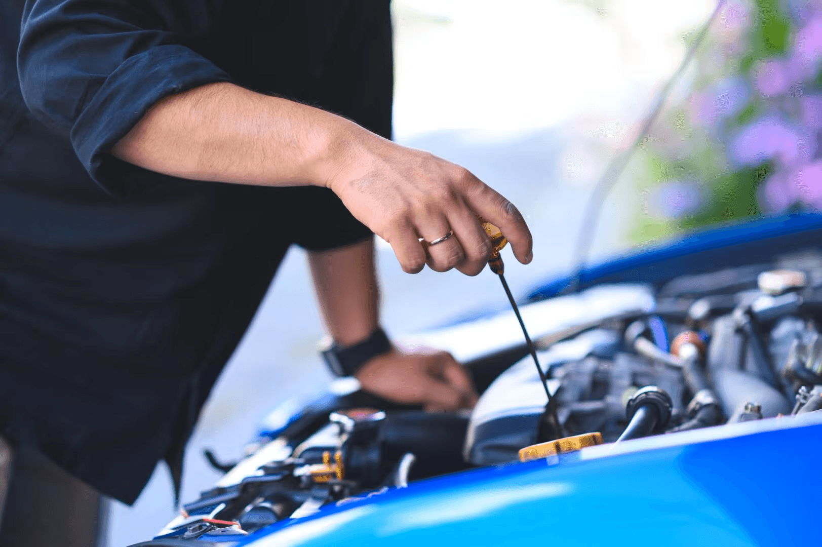 A person checking a car's oil level with a dipstick.